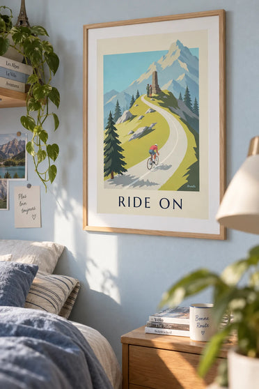 Plakat med cykelrytter på vej op ad et bjergpas: indrammet på væggen