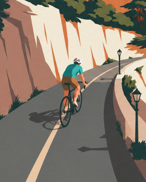 The cyclist in a turquoise jersey and white helmet, on the cliffside road lined with street lamps