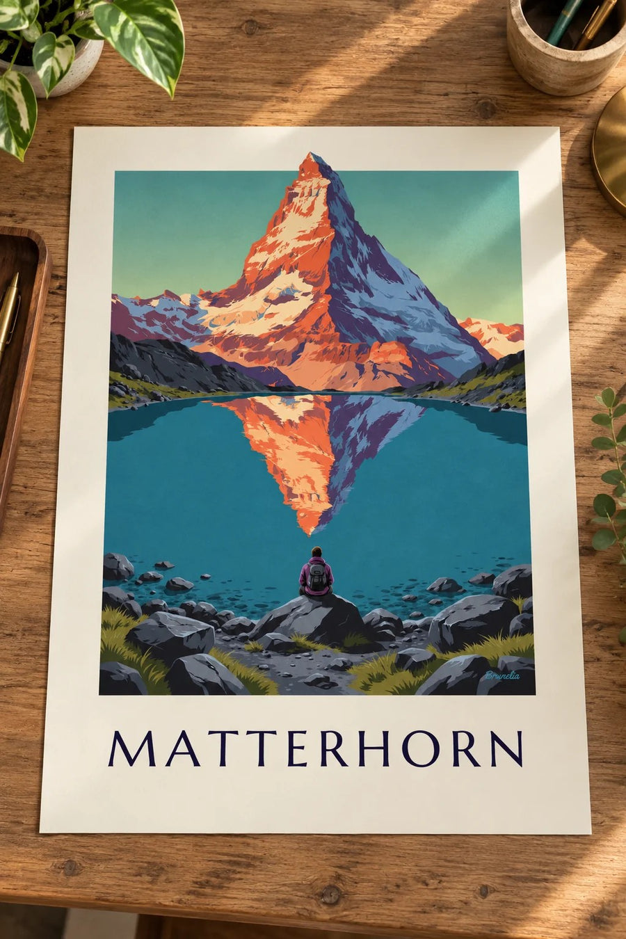 Plakat med Matterhorn ved solnedgang spejlet i en alpesø: stillet op på et bord