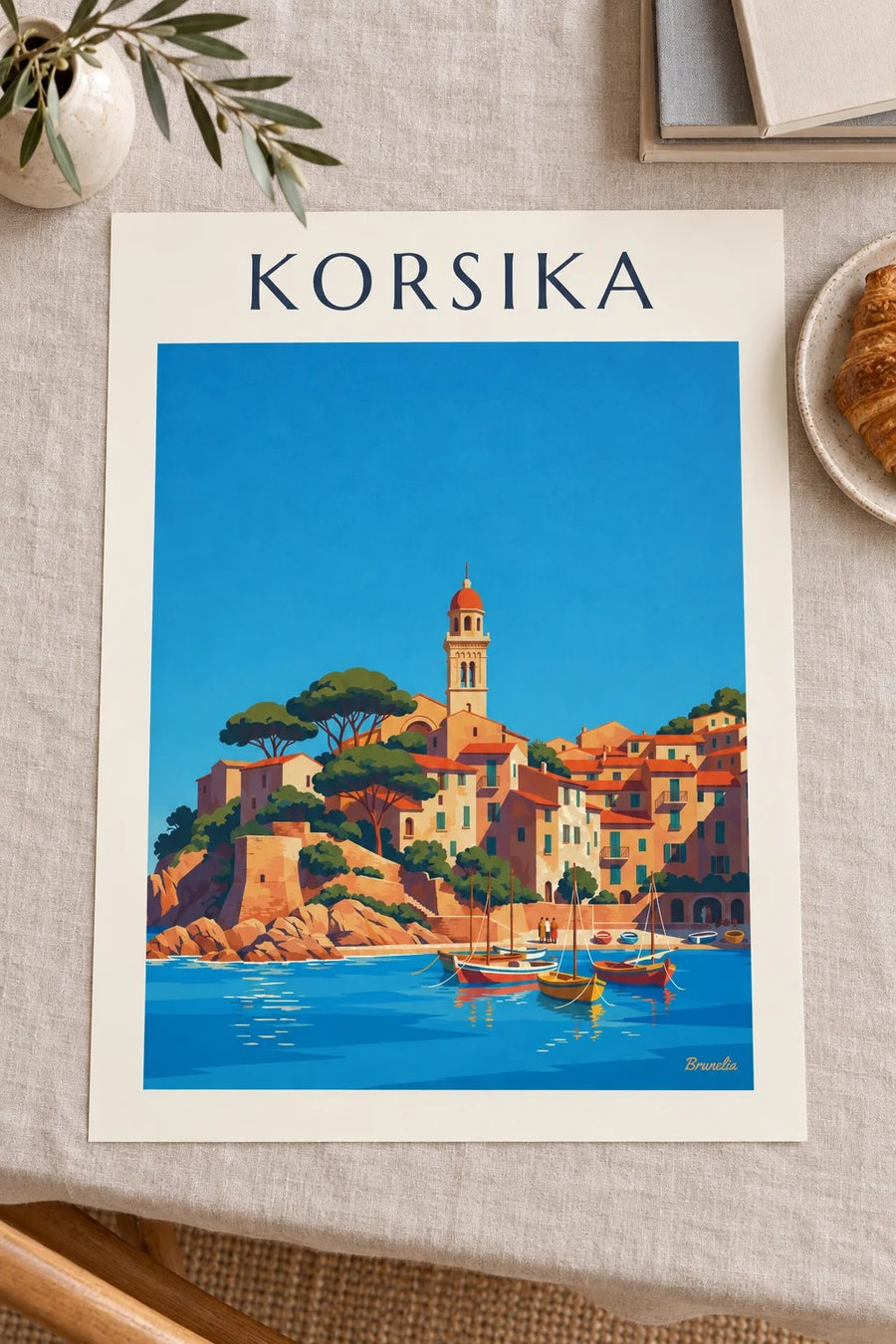 Plakat med korsikansk kystlandsby og lille havn ved Middelhavet: placeret på et bord