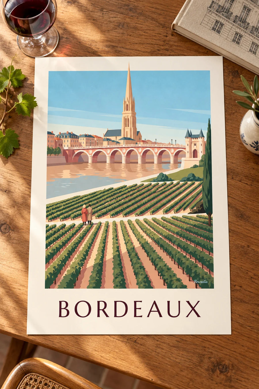 Plakat med stenbroen og Porte Cailhau i Bordeaux set fra vinmarkerne : stillet på et bord