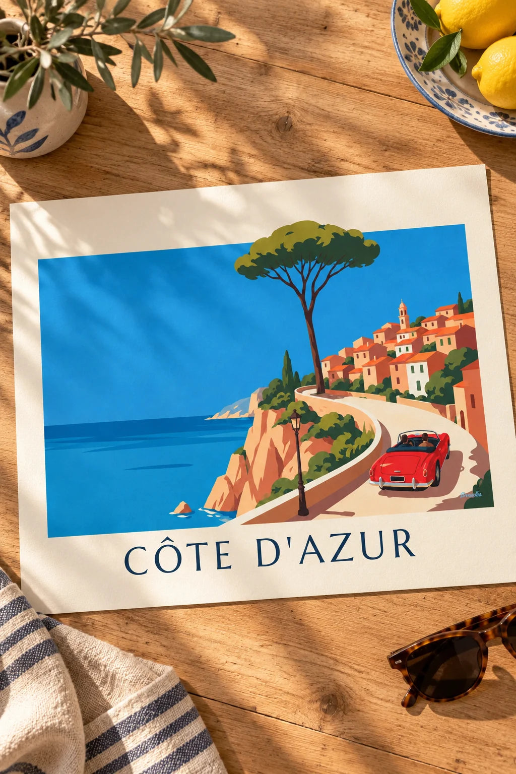Red convertible poster on a French Riviera coastal road: resting on a table