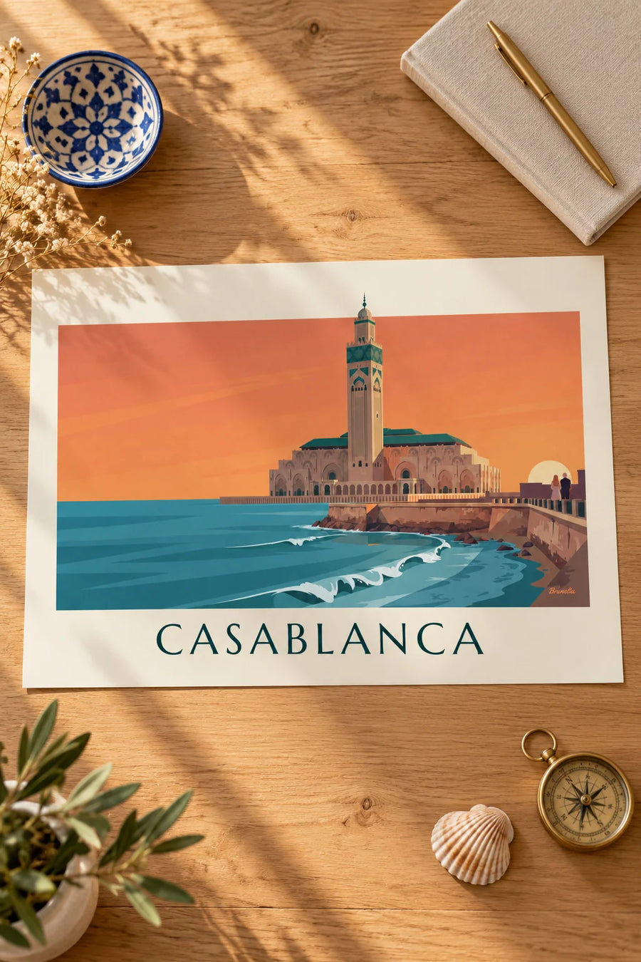 Plakat med Hassan II-moskeen ved havet i solnedgang: på et bord